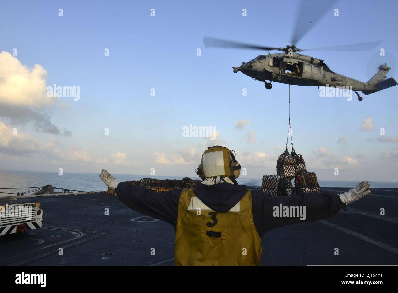 U.S. Navy Aviation Boatswain's Mate (Handling) directs an MH-60S ...