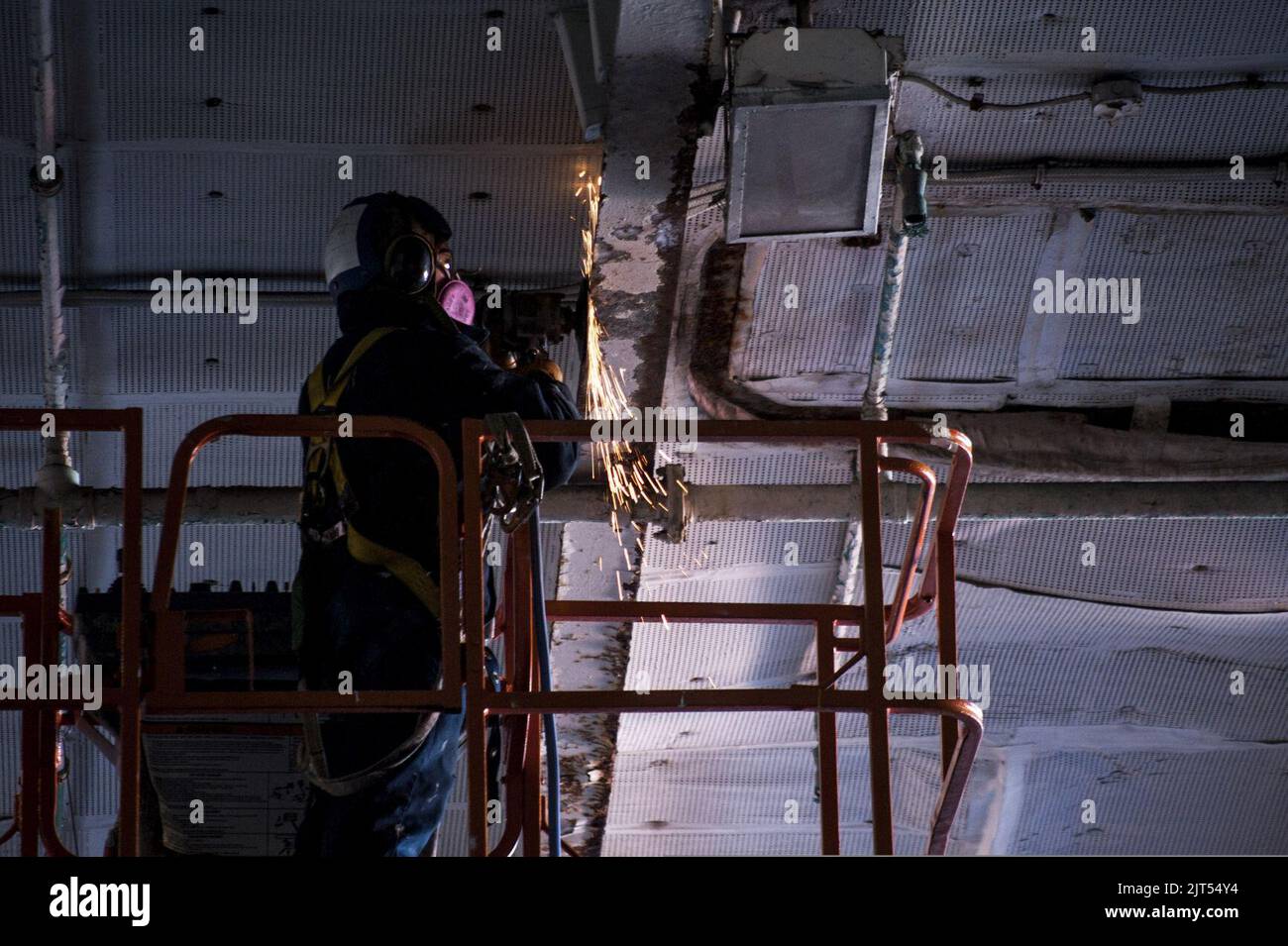 U.S. Navy Aviation Boatswain's Mate Airman grinds paint in the hangar bay of the aircraft carrier USS George Washington (CVN 73) in Yokosuka, Japan, Jan. 19, 2014 140119 Stock Photo