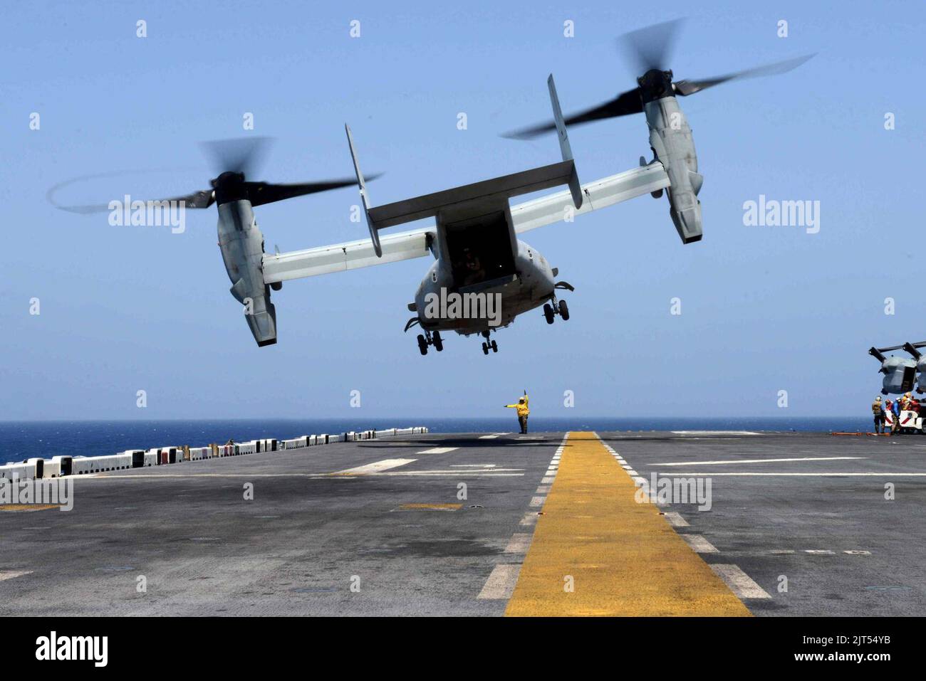 U.S. Navy Aviation Boatswain's Mate 3rd Class directs a Marine Corps MV ...