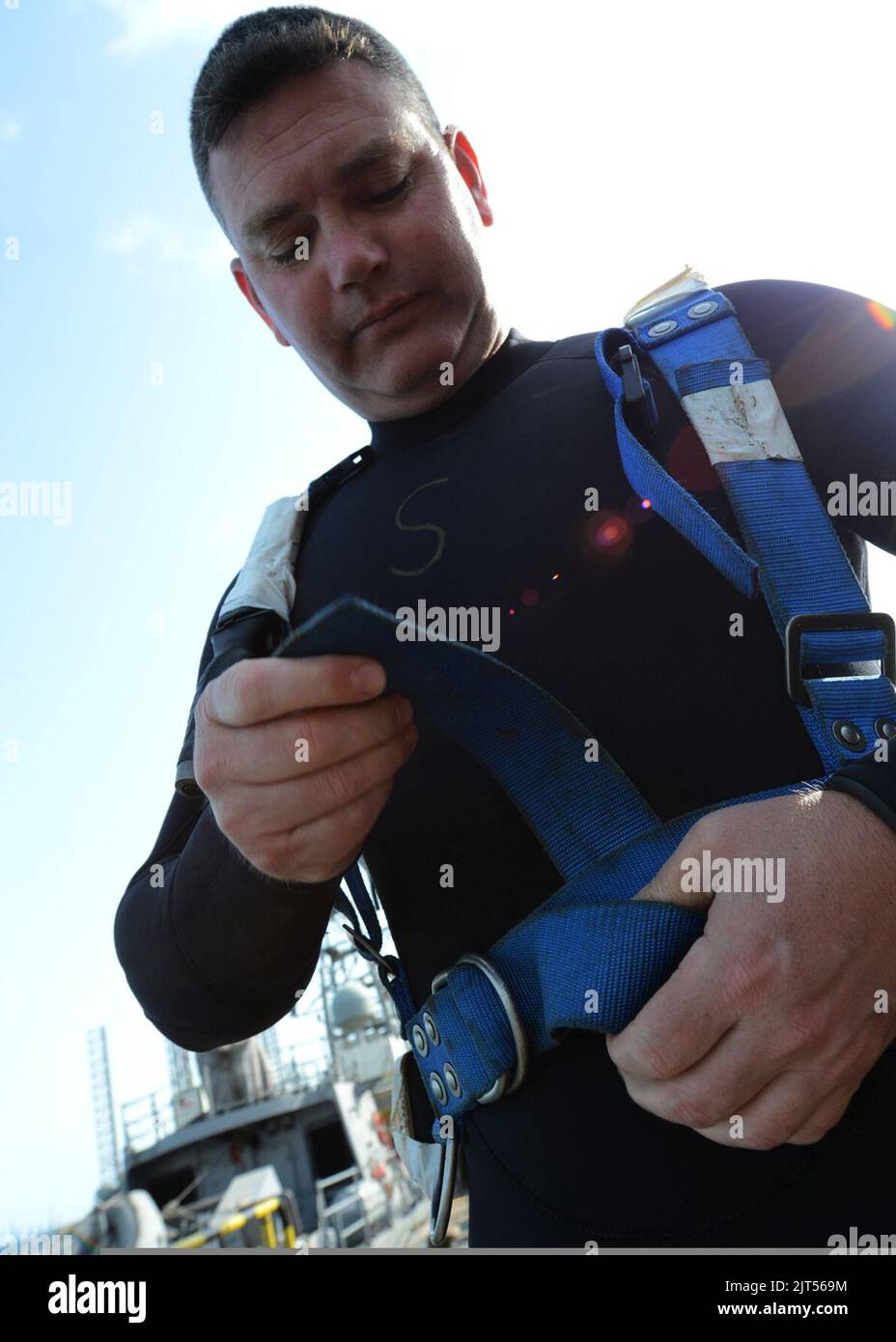 U.S. Navy Chief Warrant Officer 3 assigned to Mobile Diving and Salvage Unit (MDSU) 2 Company 2-4, fastens the harness for a Mk 20 underwater breathing apparatus prior to going into the water to 110307 Stock Photo