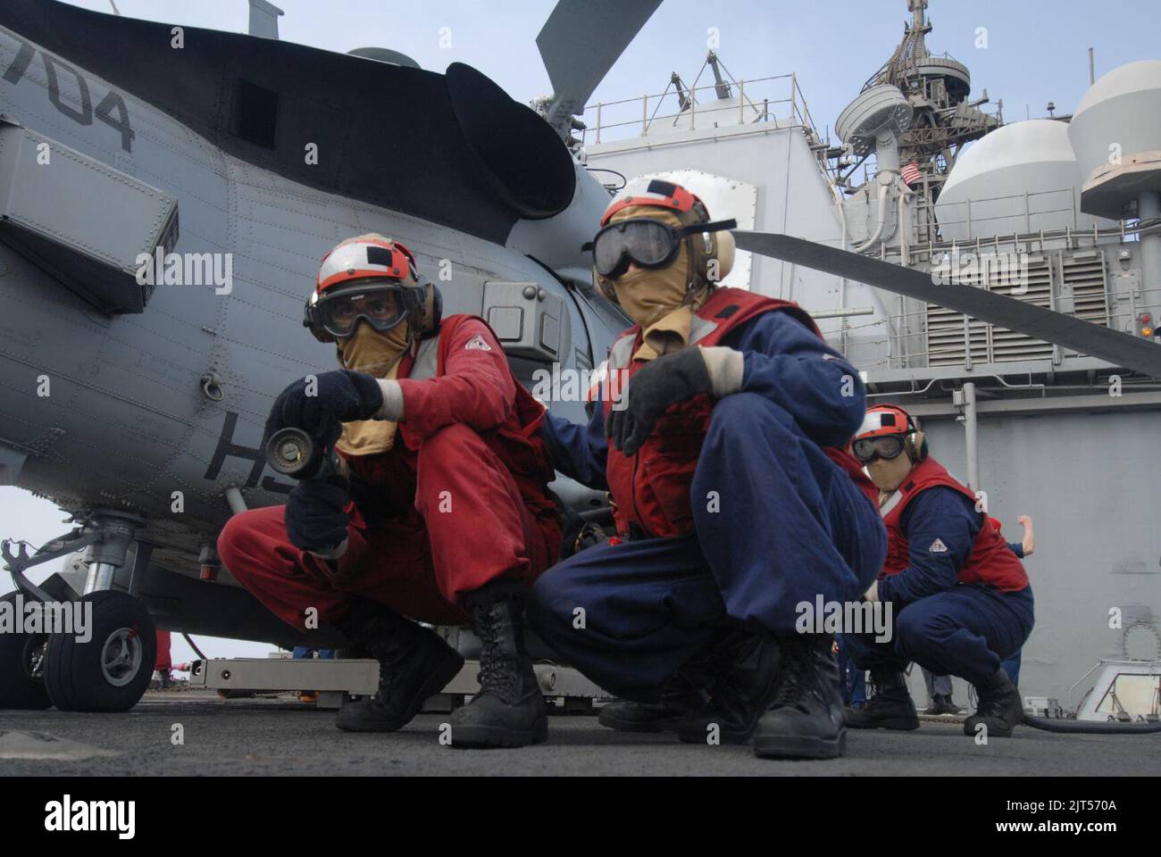 U.S. Navy Damage Controlman 1st Class right foreground, instructs Hull Maintenance Technician Fireman left, on proper hose handling techniques during a crash and salvage drill 110730 Stock Photo