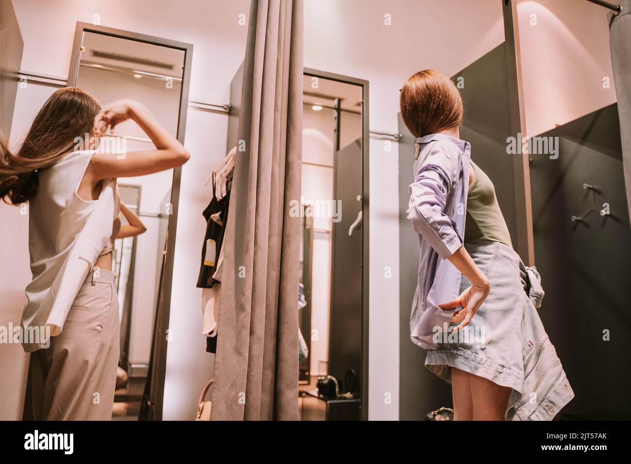 Two pretty best friends looking at the mirror at the changeing room
