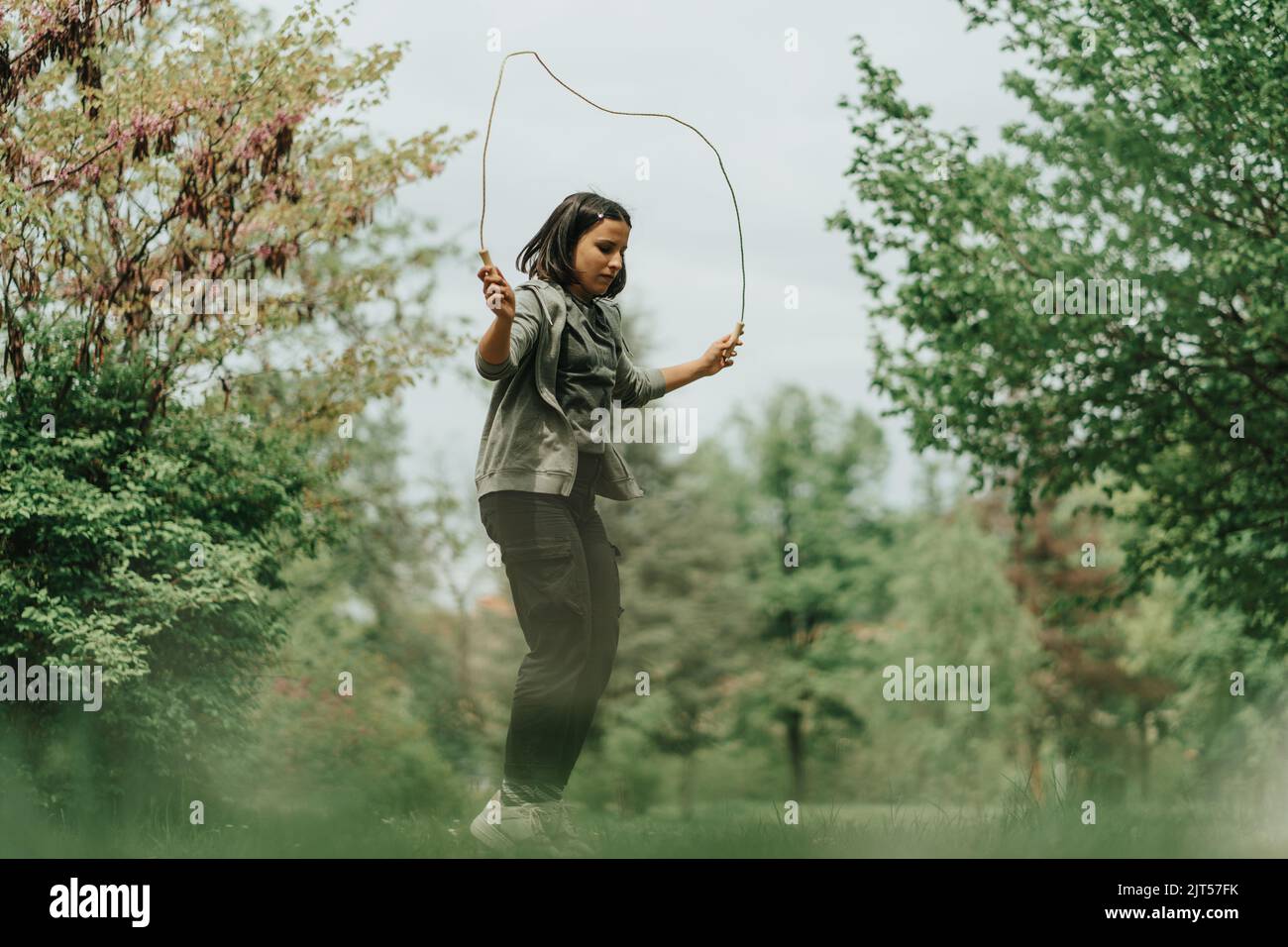 Cute sportist girl jumping on the rope in the park Stock Photo - Alamy