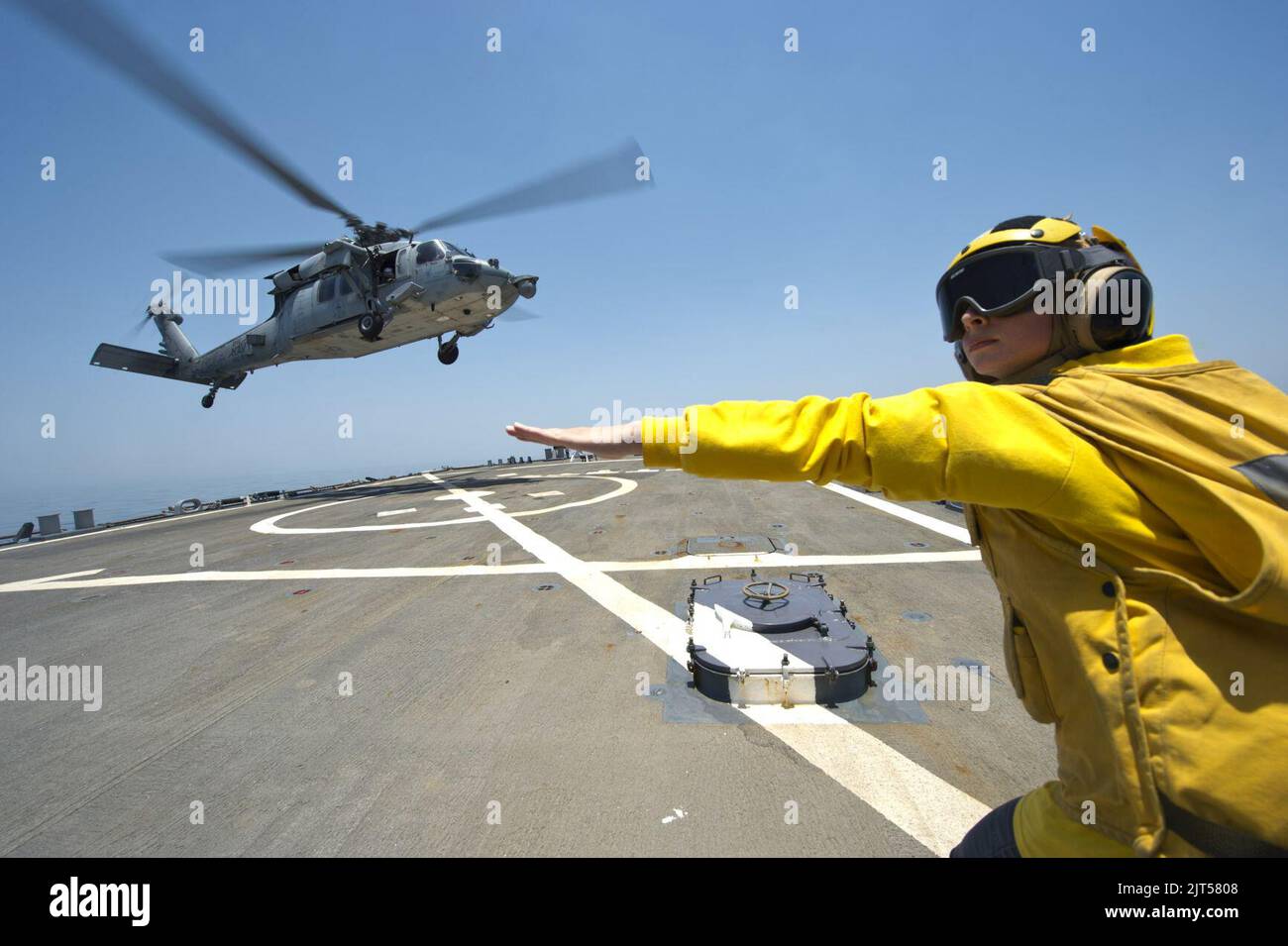 U.S. Navy Lt. j.g. guides an MH-60S Seahawk helicopter attached to Helicopter Sea Combat Squadron (HSC) 9 to take off from the guided missile destroyer USS Arleigh Burke (DDG 51) in the Persian 140628 Stock Photo