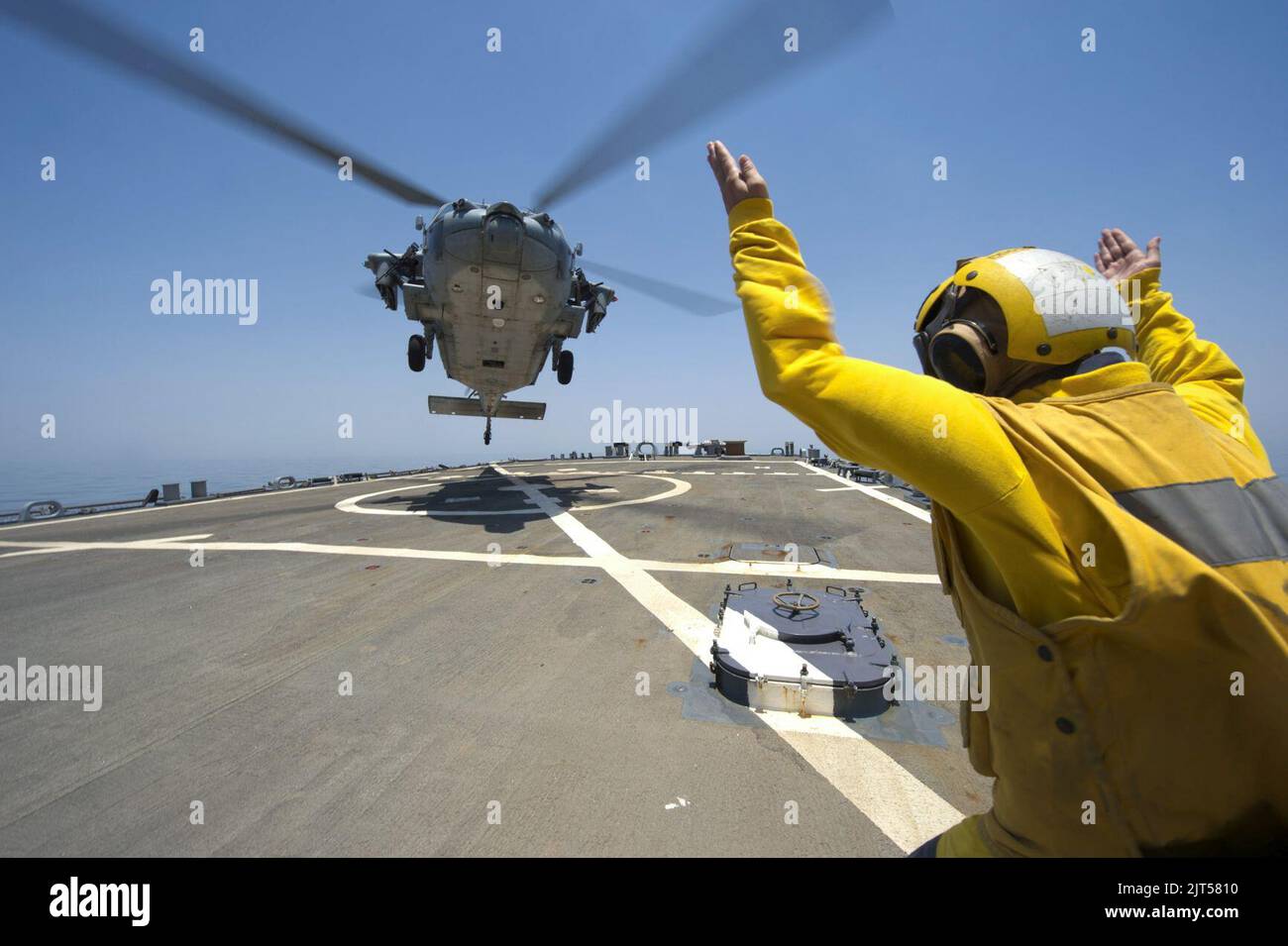 U.S. Navy Lt. j.g. guides an MH-60S Seahawk helicopter attached to Helicopter Sea Combat Squadron (HSC) 9 on the guided missile destroyer USS Arleigh Burke (DDG 51) in the Persian Gulf June 28 140628 Stock Photo