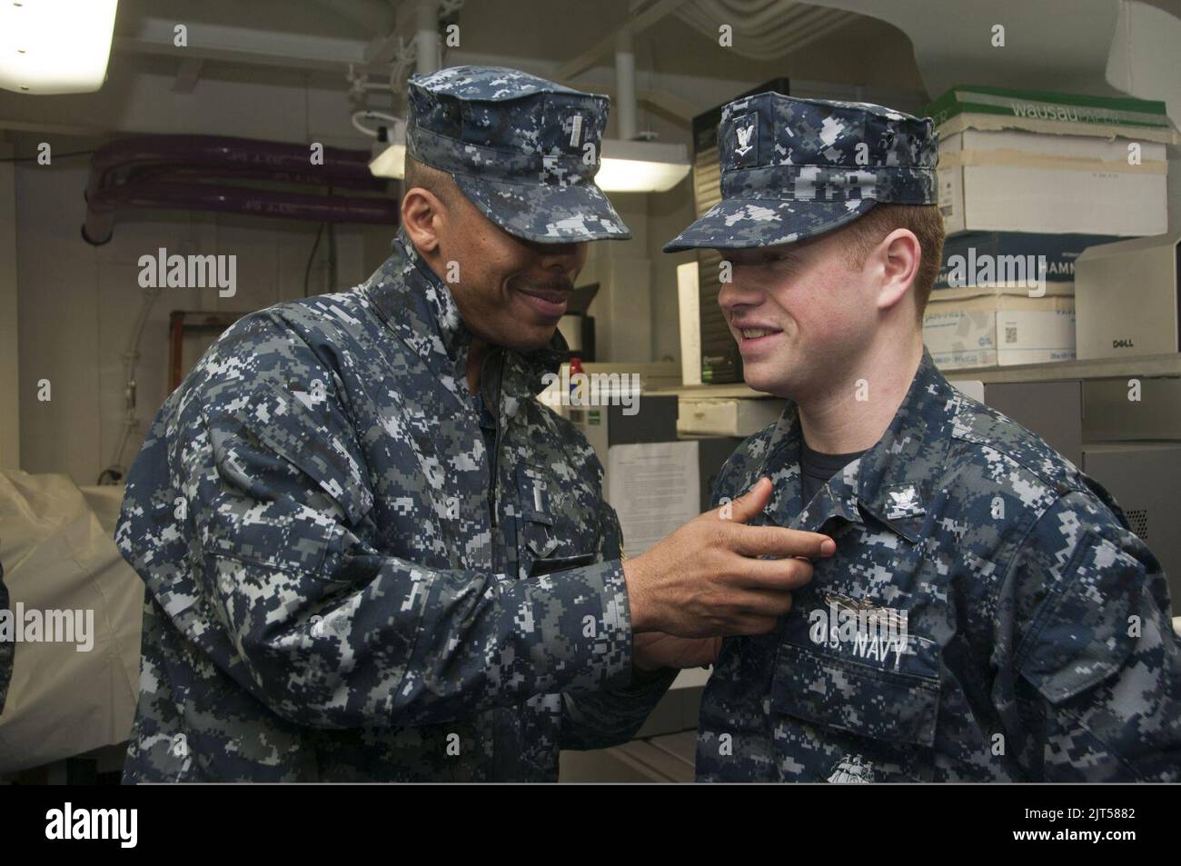 U.S. Navy Mass Communication Specialist 3rd Class right, is awarded an enlisted surface warfare specialist pin by Lt. j.g. the assistant public affairs officer for the aircraft 140115 Stock Photo