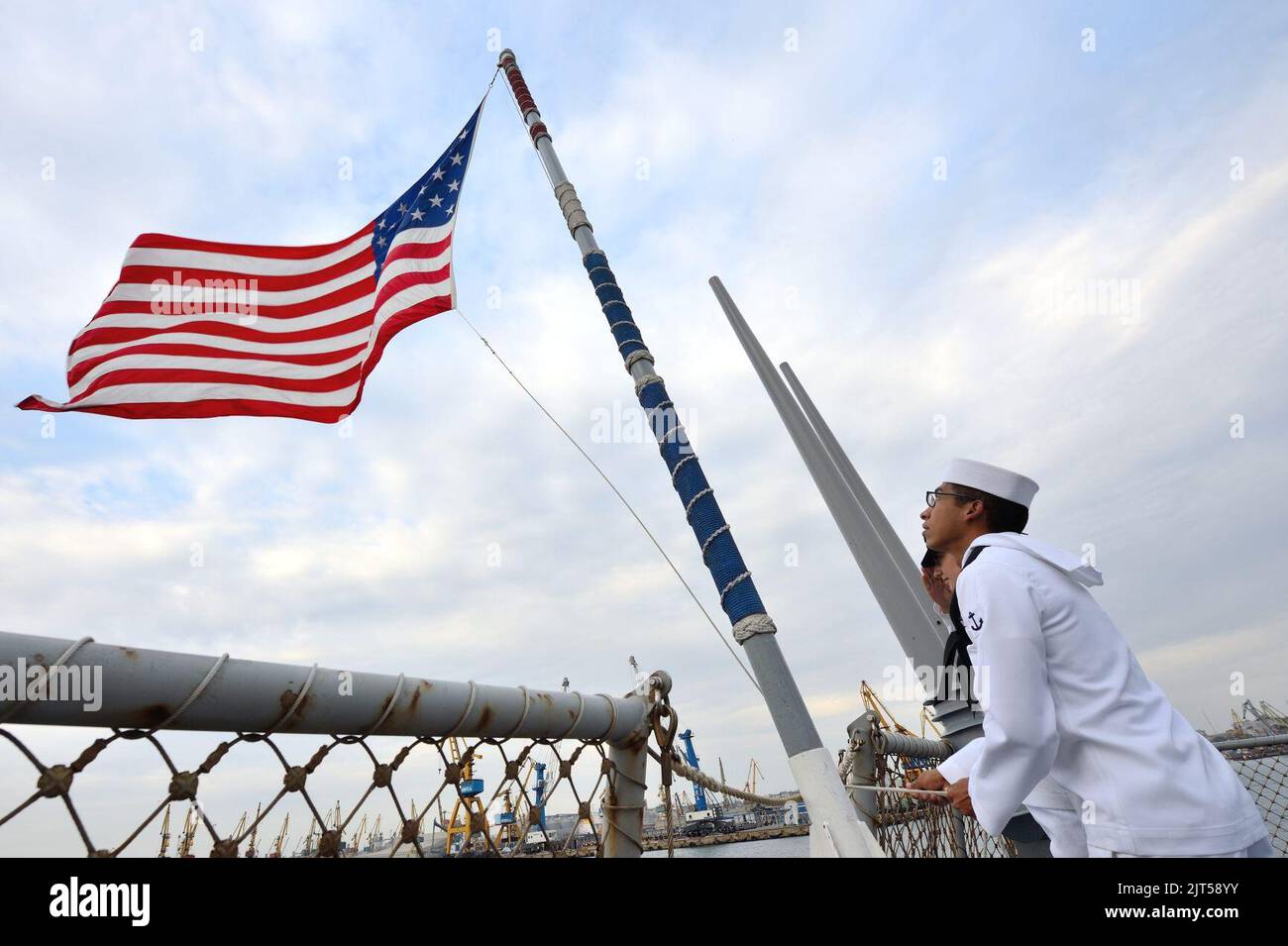 U.S. Navy Seaman raises the national ensign aboard the guided missile ...