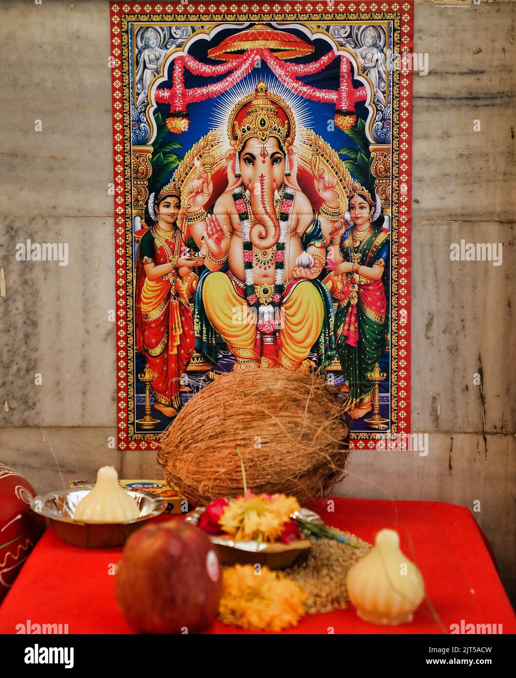 A closeup vertical shot of the God Ganesha wallpaper on the wall with a red table in front Stock Photo