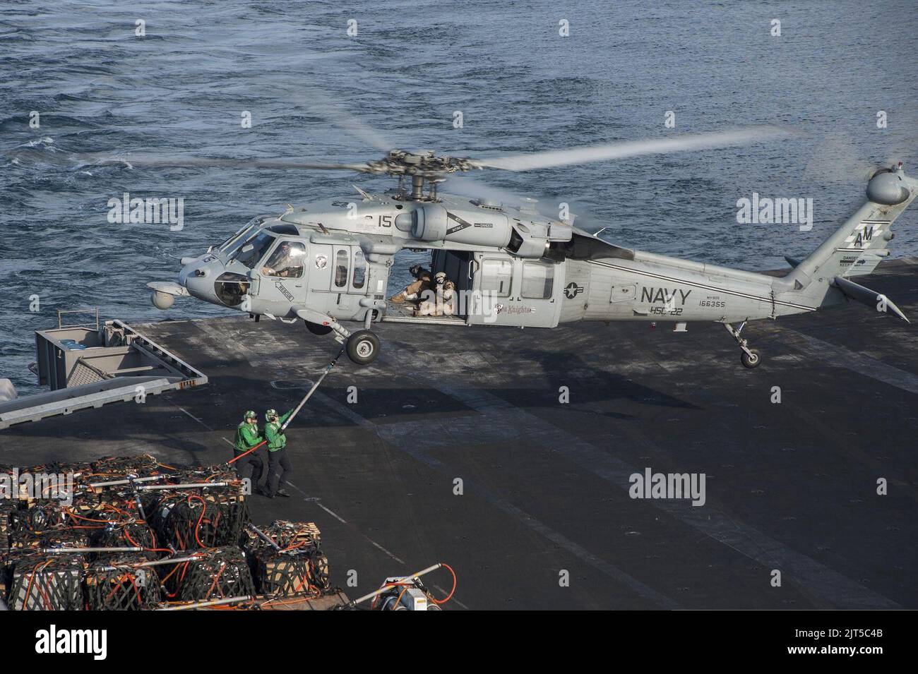 U.S. Sailors attach cargo to a Navy MH-60S Seahawk helicopter assigned to Helicopter Sea Combat Squadron (HSC) 22 on the flight deck of the aircraft carrier USS Harry S. Truman (CVN 75) during a replenishment 140307 Stock Photo