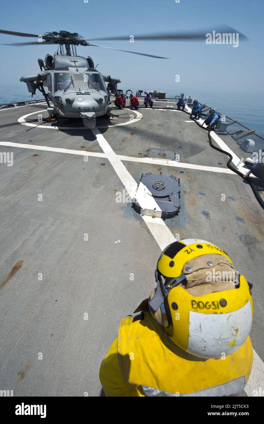 U.S. Sailors refuel an MH-60S Seahawk helicopter attached to Helicopter Sea Combat Squadron (HSC) 9 on the guided missile destroyer USS Arleigh Burke (DDG 51) in the Persian Gulf June 28, 2014 140628 Stock Photo