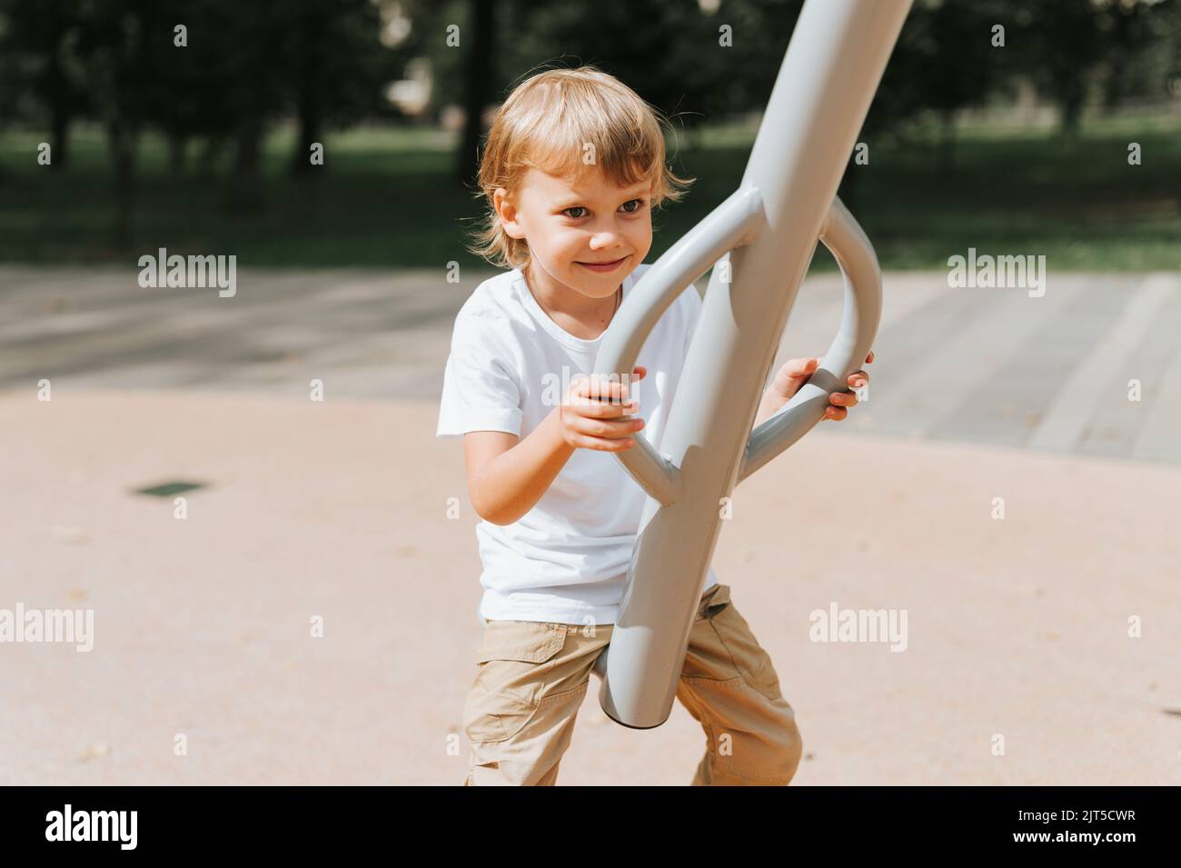 kid on the city playground swings on a swing carousel. cute little happy smiling candid five