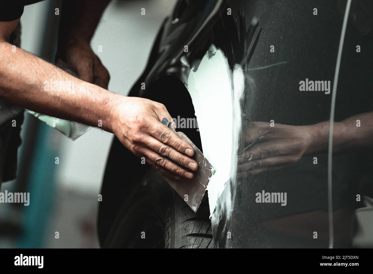 A hand working with an iron piece and repairing a car Stock Photo Alamy