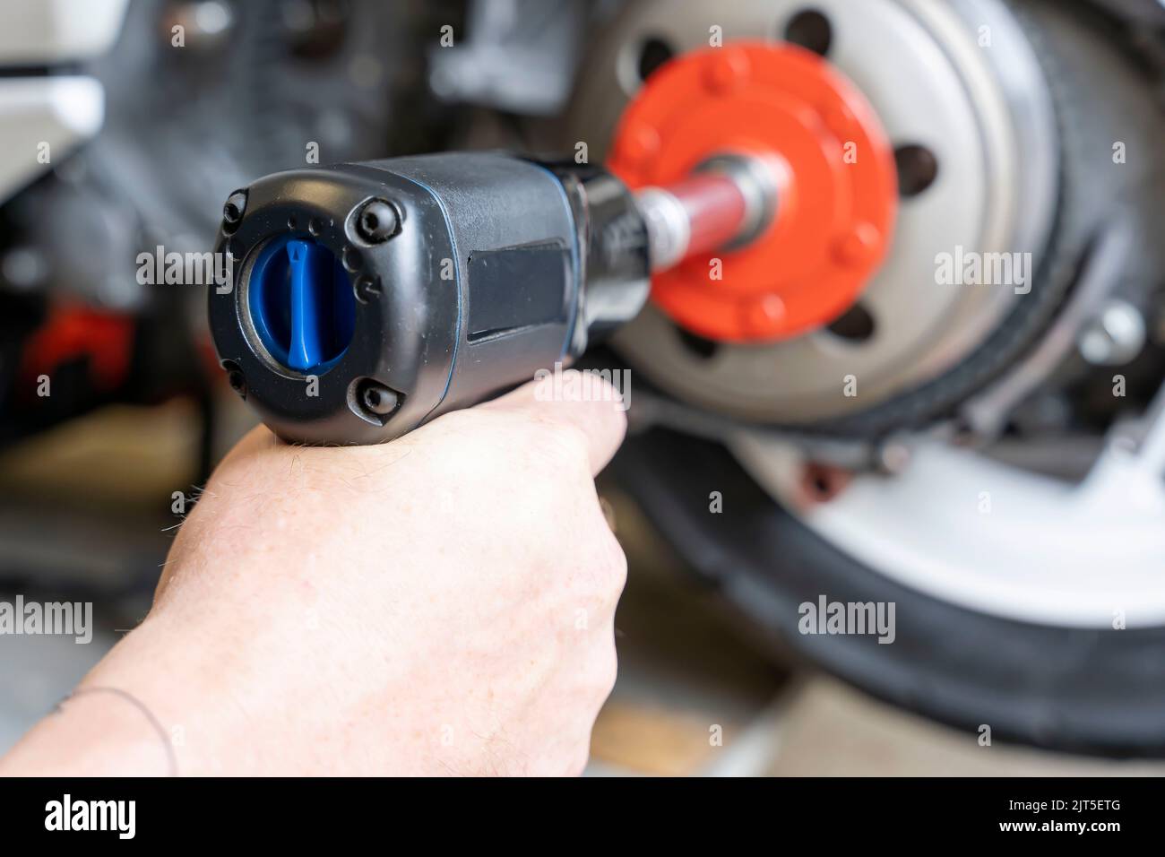 master's hand unscrews the torque driver nut on the scooter variator