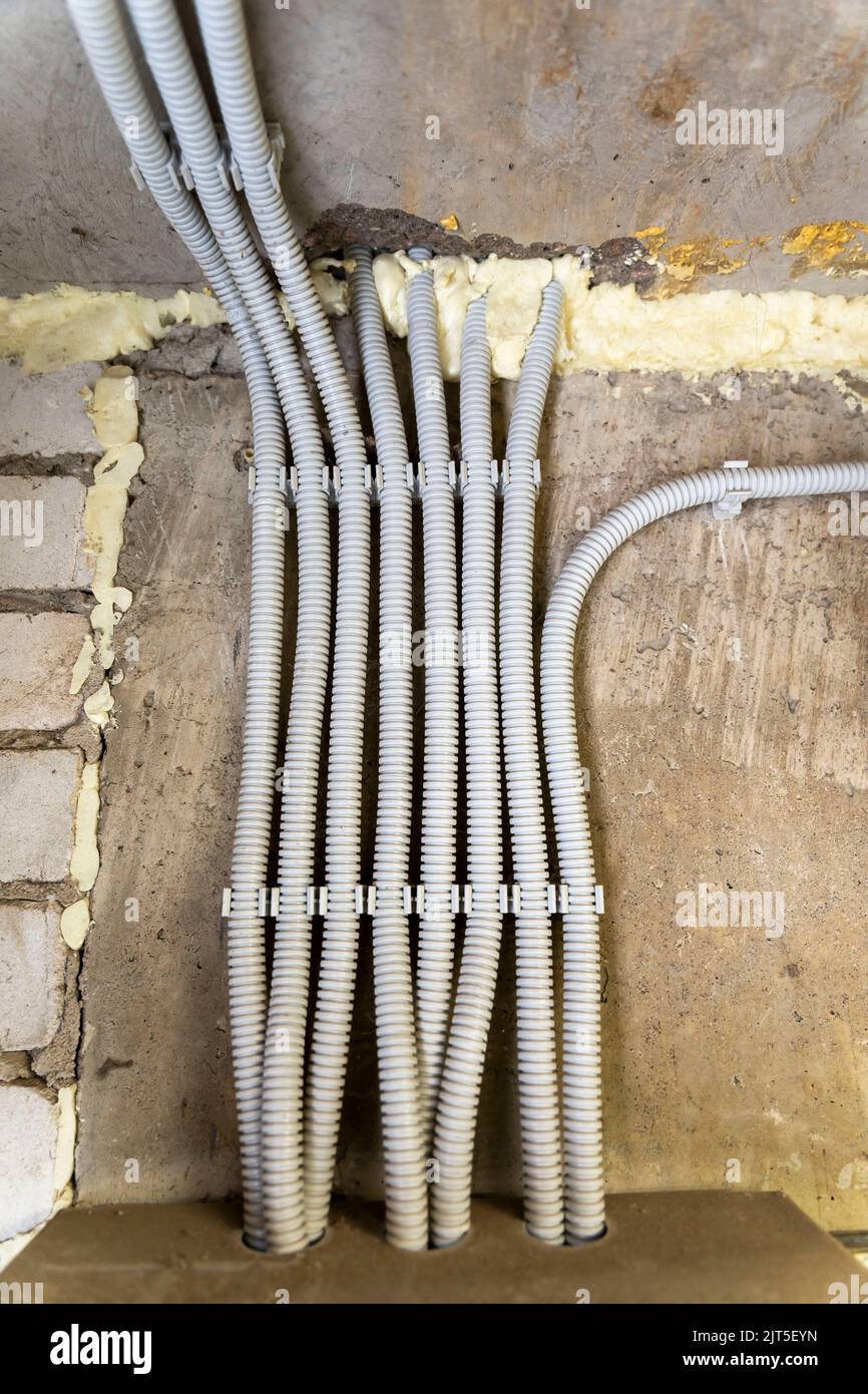there are a lot of wires in corrugated hoses laid on a concrete wall Stock Photo