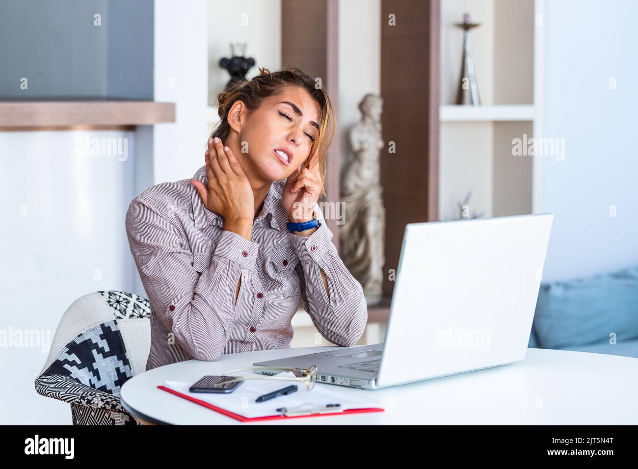 Feeling exhausted. Frustrated young woman looking exhausted while sitting at her working place and carrying her glasses in hand Stock Photo
