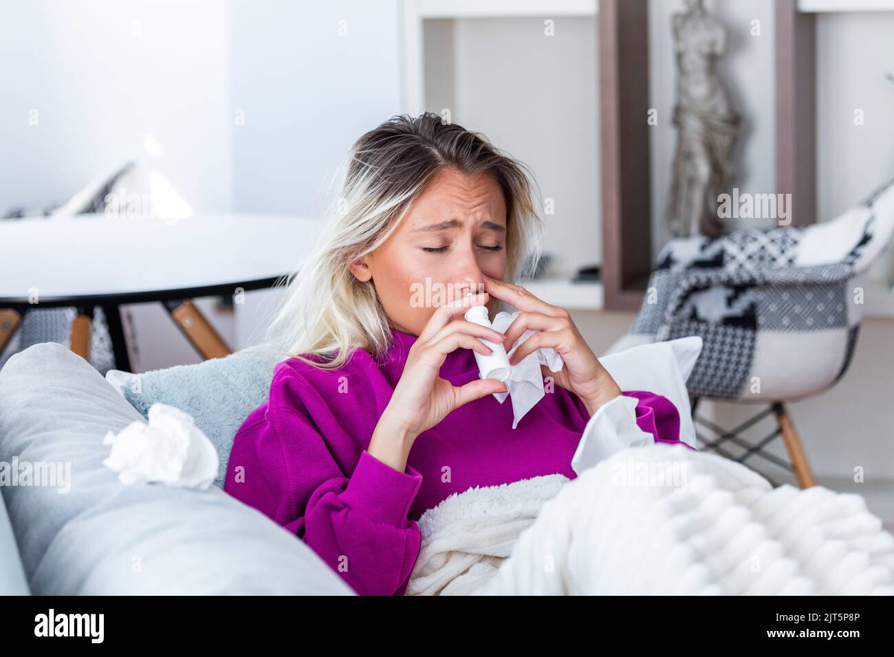 Woman is having flu and she is using nasal spray to help herself. Woman