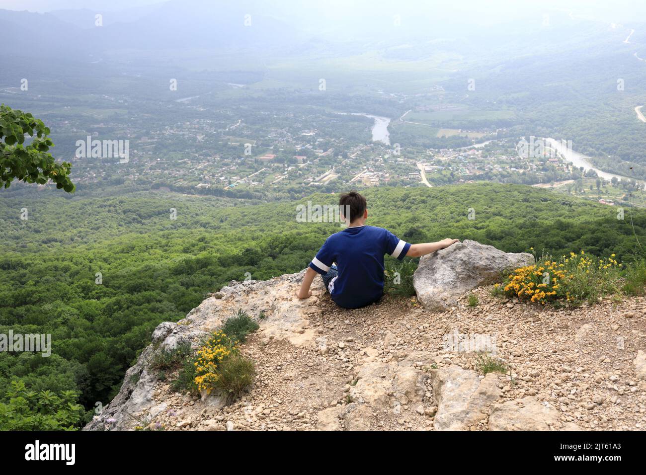 Boy sitting on rock of Una-koz ridge in Caucasus, Adygea Stock Photo ...