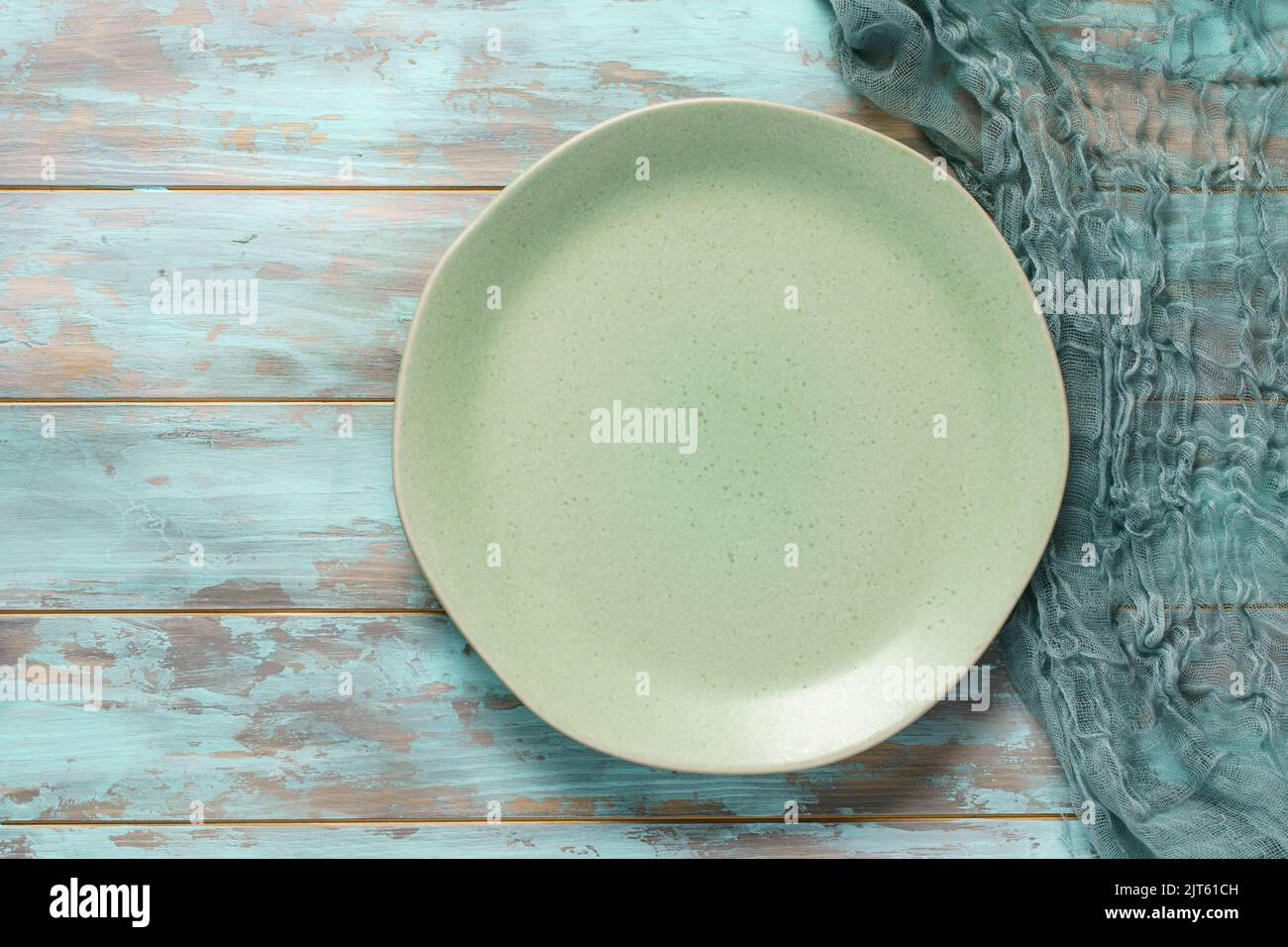Empty green plate and gauze napkin on old shabby blue wooden table. Top view, with copy space Stock Photo