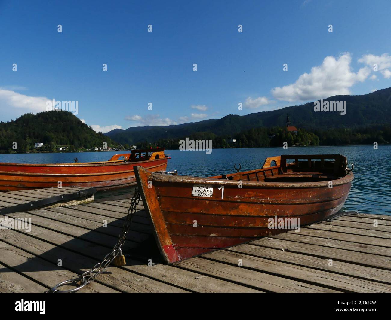 An old wooden boat moored to a wooden pier by the Bled Lake, Slovenia ...