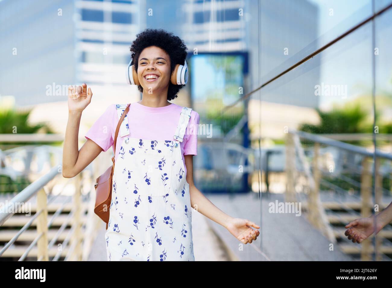 Cheerful black woman listening to music on street Stock Photo