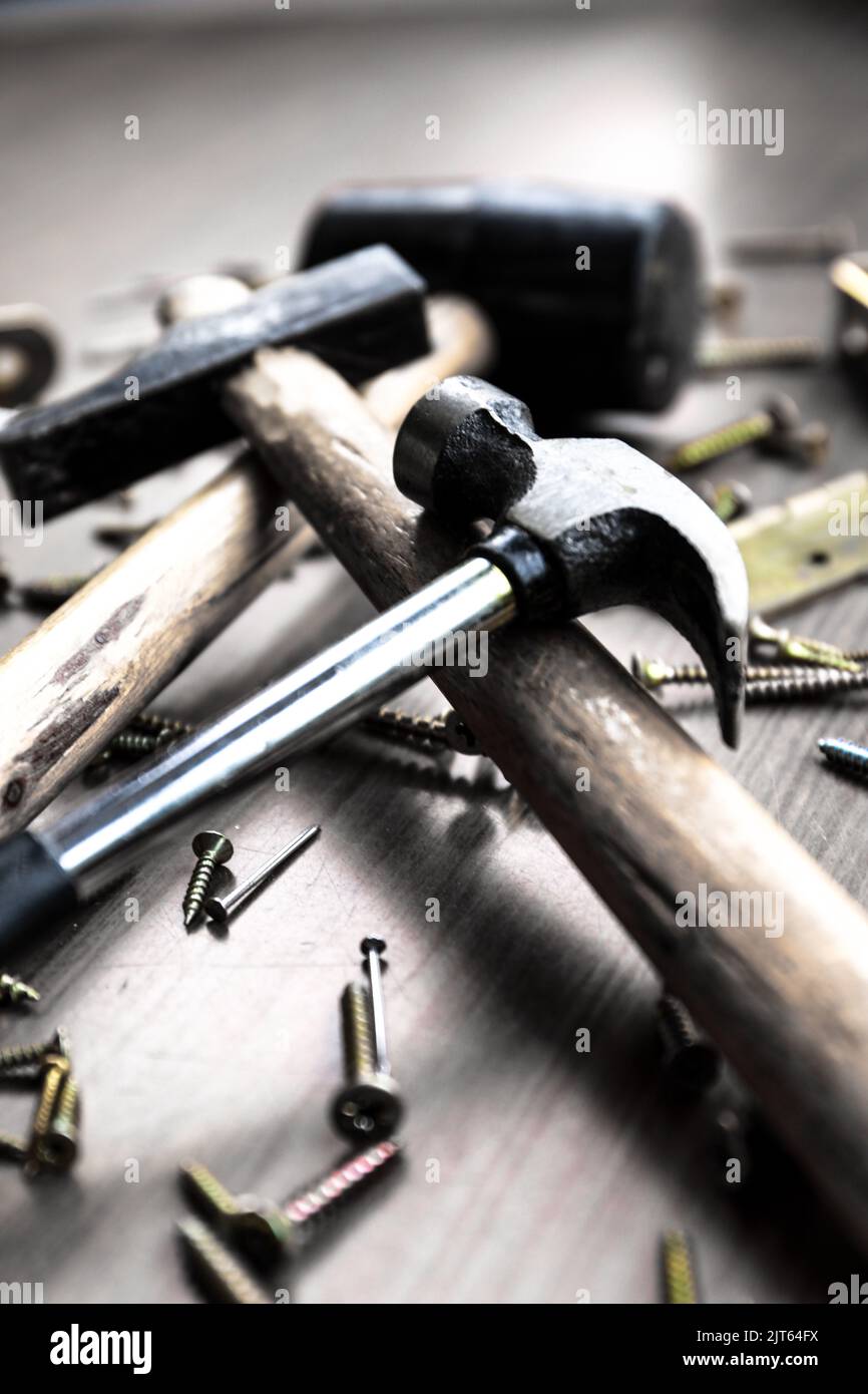 A vertical shot of a rubber mallet with a sledgehammer, claw hammer and screws on grey background. Stock Photo