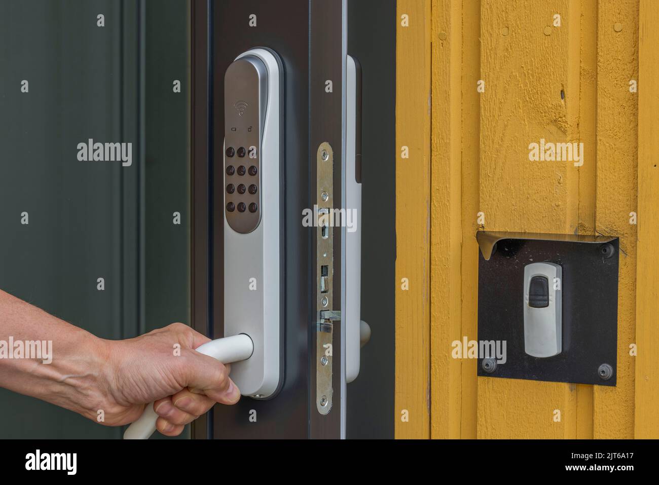 View of man's hand opening entrance door with digital lock. Sweden