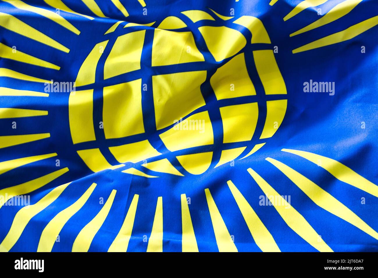 A closeup shot of deep tones of the ruffled flag of Commonwealth Symbol Visual Identity Stock Photo