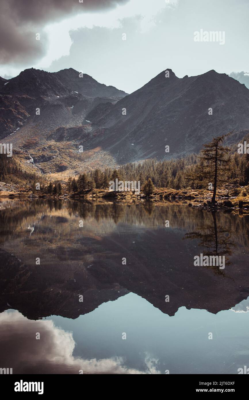 A vertical shot of a lake with reflection of mountains in it in autumn ...