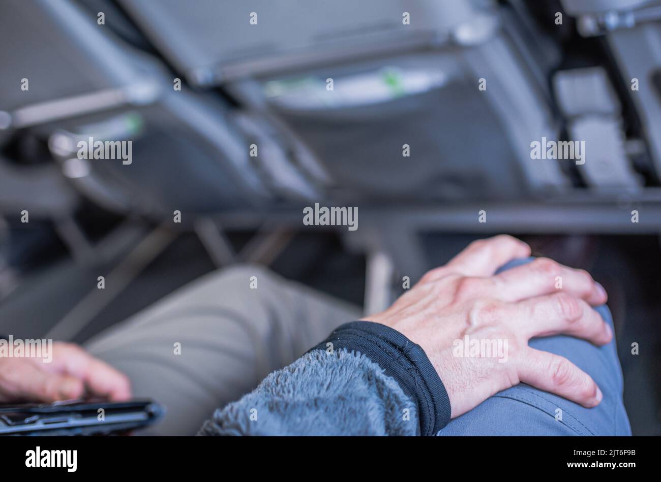 Man expresses fear of flying by gripping partner's knee. Stock Photo