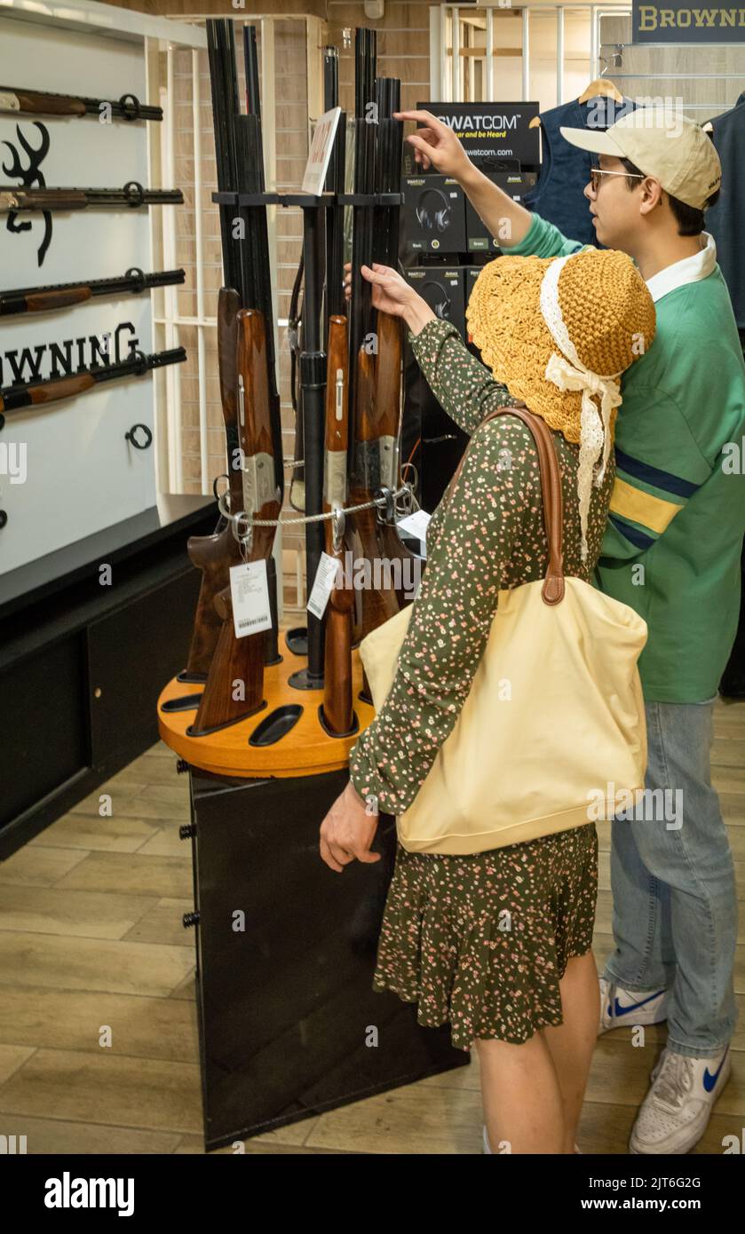 An Asian woman and her son look at 12-bore shotguns for sale in the shop at Southdown Gun Club & Shooting School, Findon, West Sussex, UK. Stock Photo