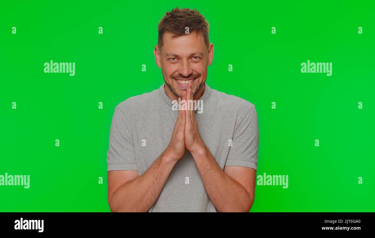 Sneaky cunning handsome man with tricky face gesticulating and scheming evil plan, thinking over devious villain idea, cunning cheats, jokes and pranks. Adult guy on green chroma key studio background Stock Photo
