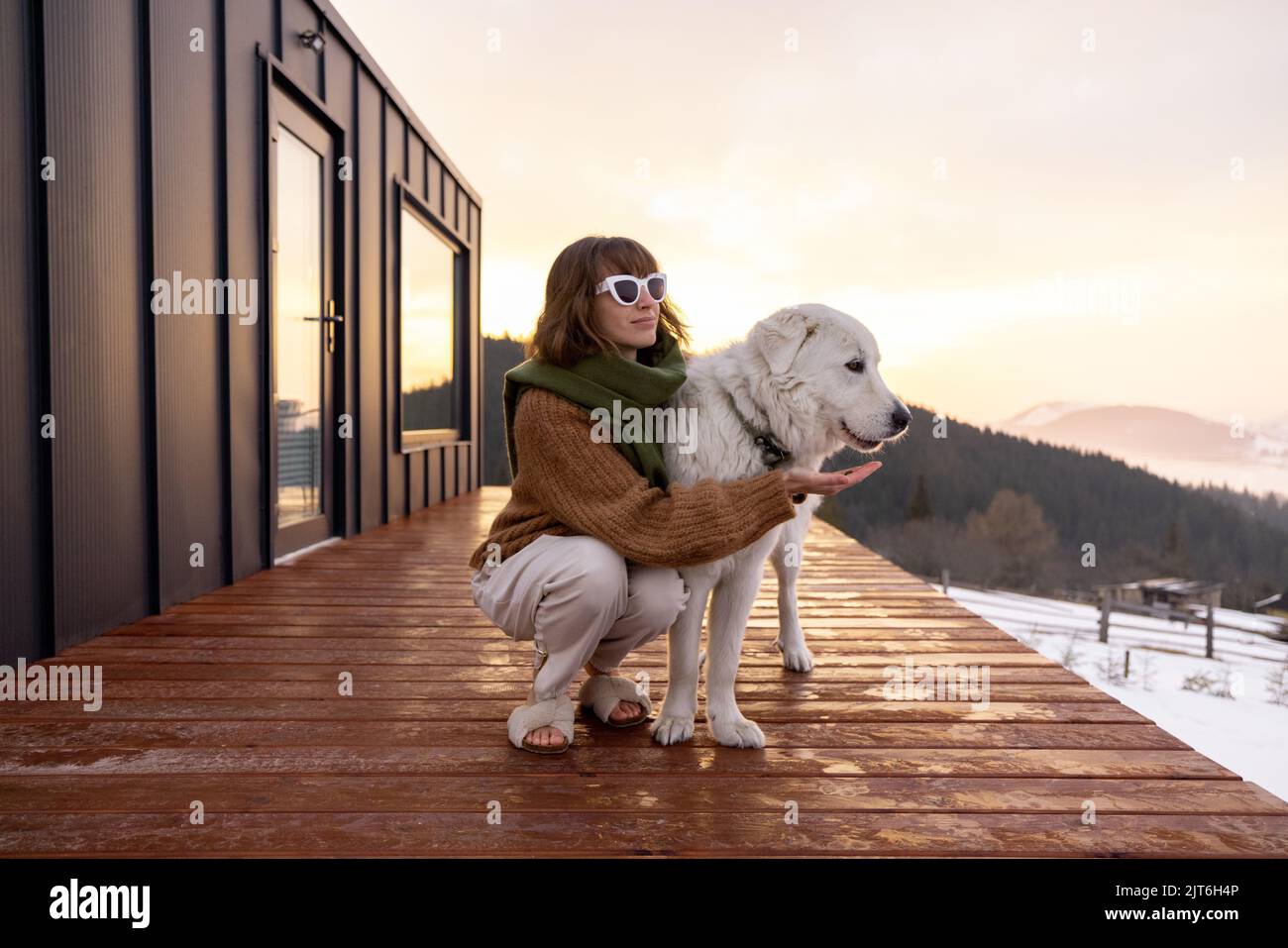 Woman with her dog resting on terrace of tiny house on nature Stock ...