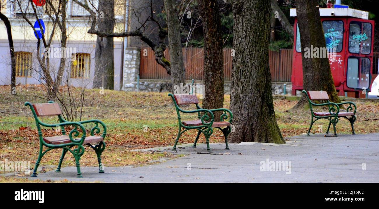 A row of empty benches on the side of a walkway in a park Stock Photo ...