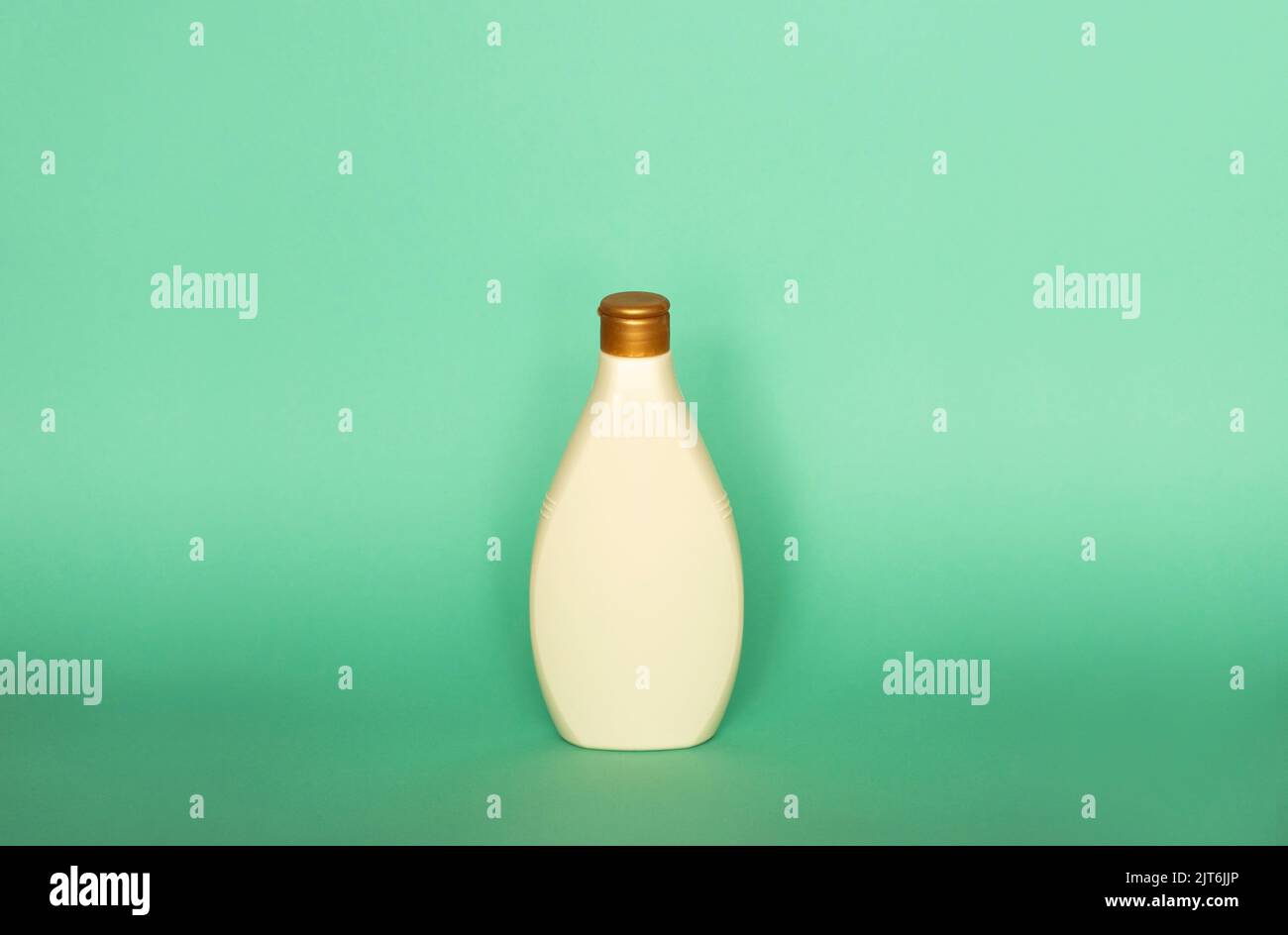 Beige blank plastic bottles isolated on green background. Stock Photo