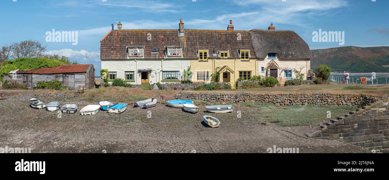 At low tide a row of small boats lie on the shingle in font of the small cottages at Porlock Weir in Somerset. Stock Photo