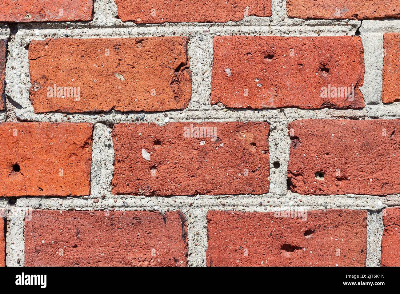 Close-up of several old bricks of vintage wall old cathedral with wartime bullet holes. Background of brick wall texture. Red brick and joints gray ce Stock Photo
