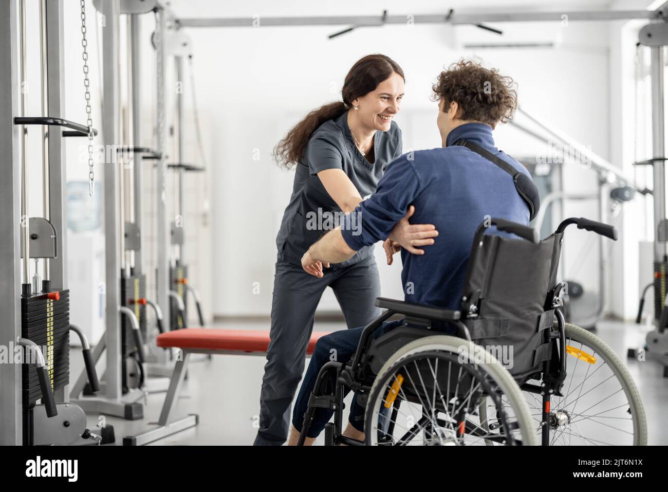 Rehabilitation specialist helps a guy stand out of a wheelchair Stock Photo Alamy