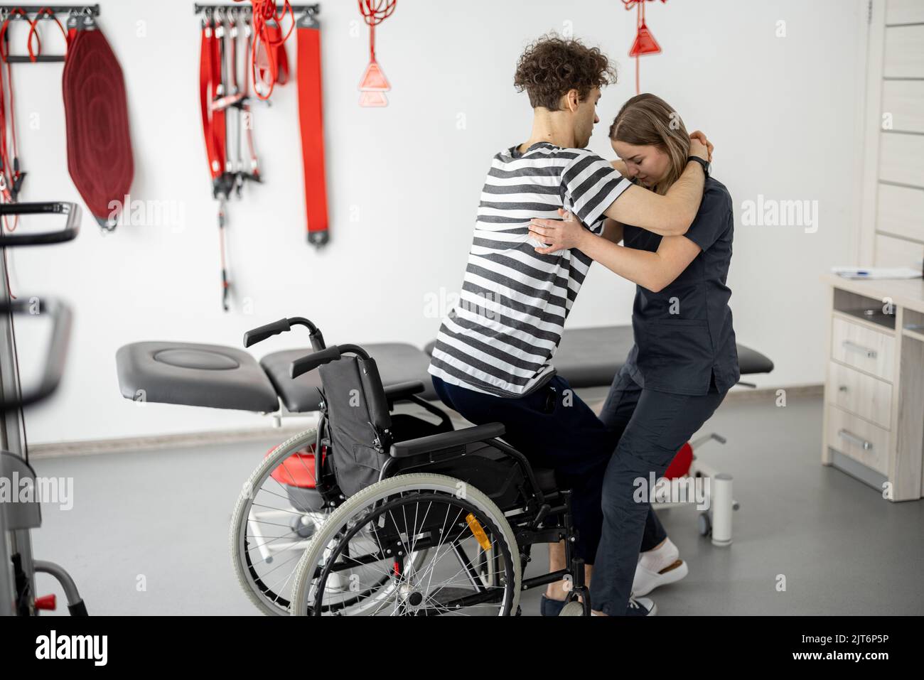 Nurse of the rehabilitation center helps man to get up from a