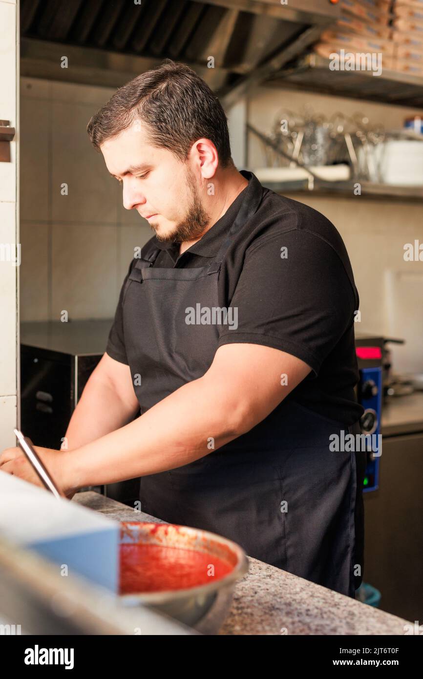 Latin Pizzeria chef cook pizza in professional uniform. restaurant