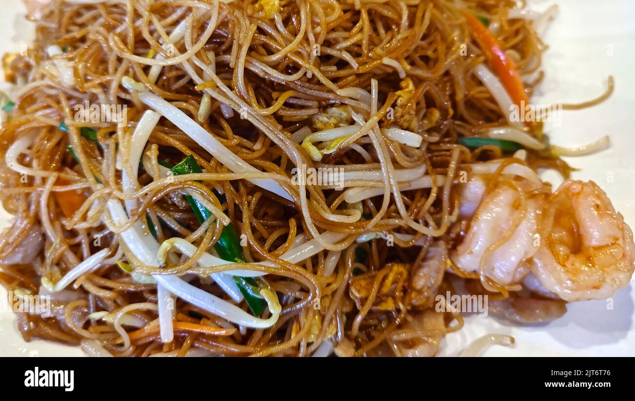 Authentic stir-fry rice noodles with shrimp and bean sprouts. Close-up on a plate. Horizontal top view Stock Photo