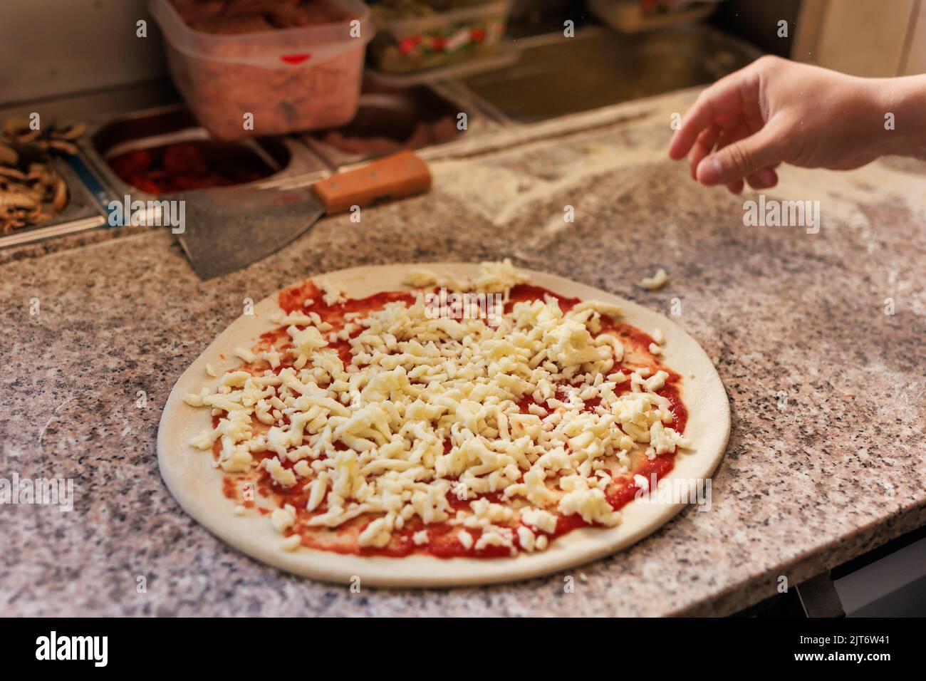 Pizzeria chef unrecognizable hands preparing a fresh pizza