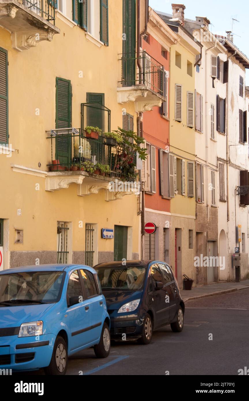 Street scene, Parma, Emiglia Romagna, Italy.  Houses painted in bright colours with shutters and balconies, cars, plants; plant pots Stock Photo