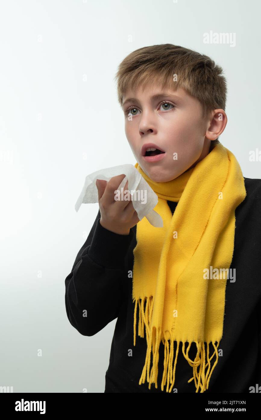 The child sneezes into a handkerchief, symptoms of colds, the boy is