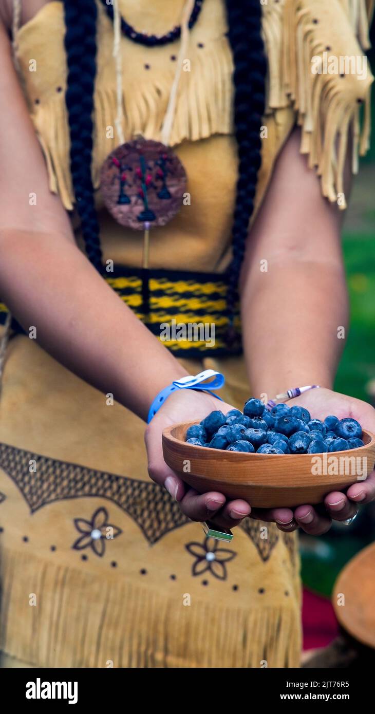 MASHANTUCKET RESERVATION, CT, USA-AUGUST 27, 2022:  Schemitzun : Feast Of green corn and dance. Native American girl is holding bowl with blueberries Stock Photo
