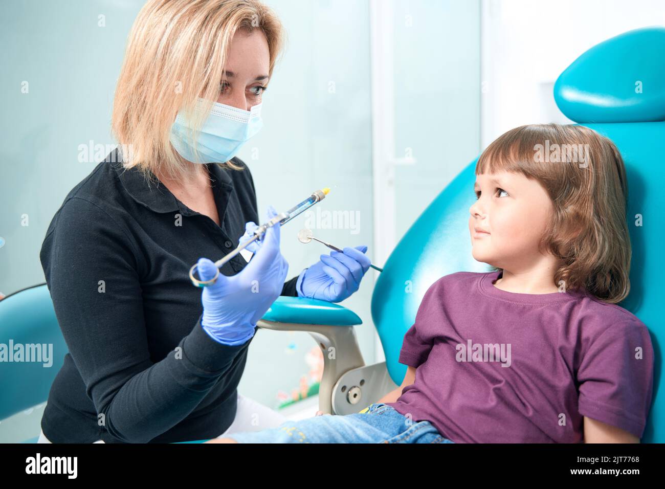 Pediatric dentist preparing to administer local anesthetic to child
