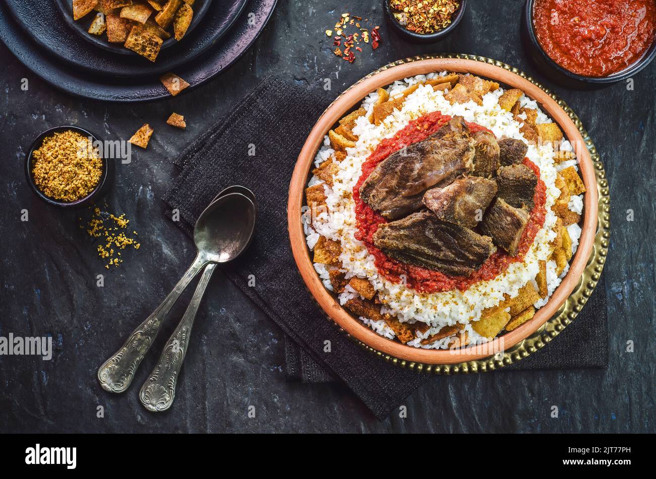 Arabic cuisine, Egyptian oriental Fettah with white rice and crispy bread topped with seasoned garlic red sauce, crispy fried garlic and veal chunks. Stock Photo