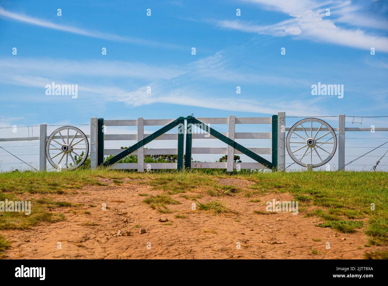 Country property gate with old ornamental wheels. Farm entrance. Rural