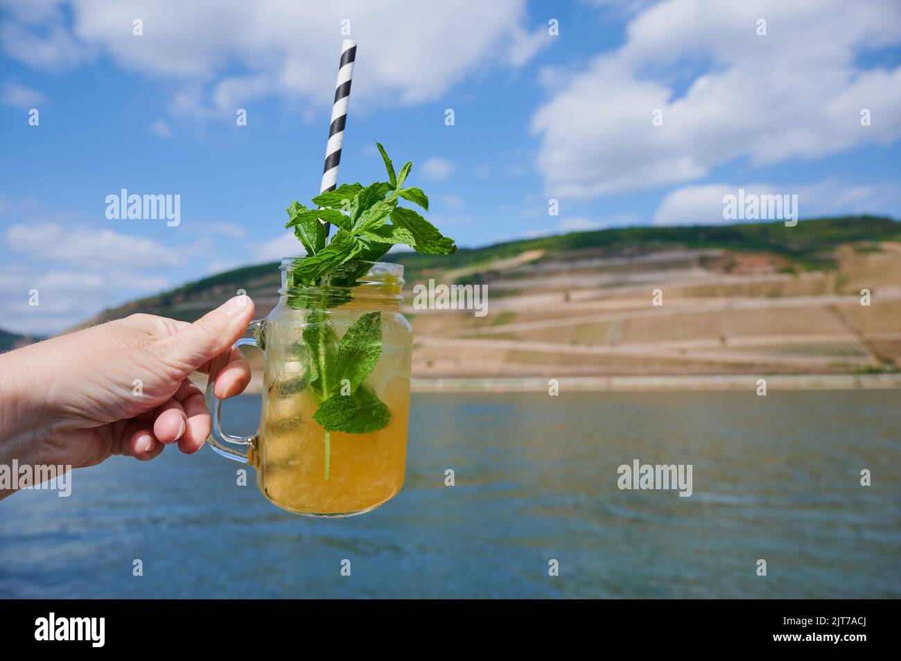 woman hand with lemonade in front of a rhine landscape in the summer Stock Photo