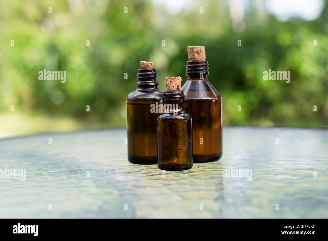 Small brown glass medicine bottles on glass table with green outdoor