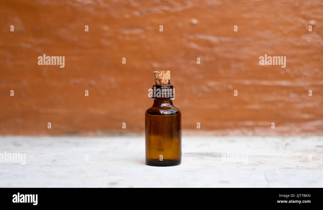 Small brown medicine bottle on white stone table and blurry orange
